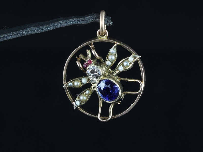 AN EDWARDIAN 9CT GOLD SAPPHIRE, SEED PEARL, RUBY AND DIAMOND FLY PENDANT 