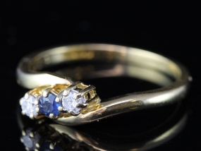 PRETTY SAPPHIRE AND DIAMOND THREE STONE CROSSOVER 18 CARAT GOLD RING