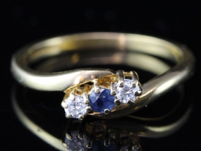 PRETTY SAPPHIRE AND DIAMOND THREE STONE CROSSOVER 18 CARAT GOLD RING